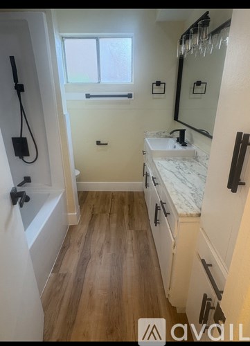 A bathroom with a white sink and wooden floors.