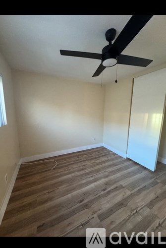 A room with a ceiling fan and wooden flooring.