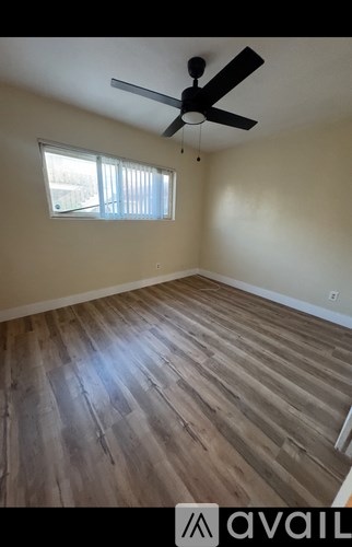 A room with wooden flooring and a ceiling fan.