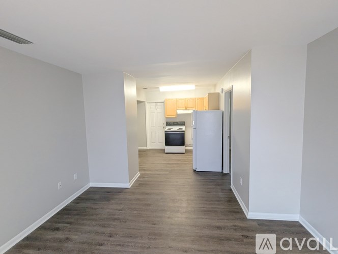 A spacious, empty room with a kitchenette in the background.