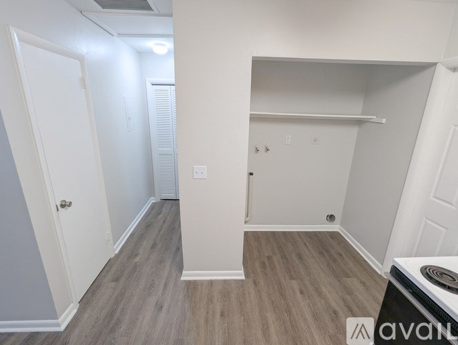 A room with a white door and a white wall with a shelf and a small table.