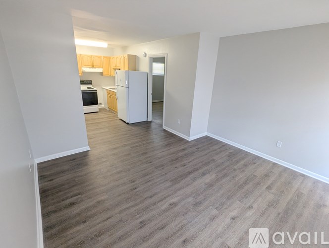 A kitchen with white appliances and wooden cabinets is visible from an open doorway.