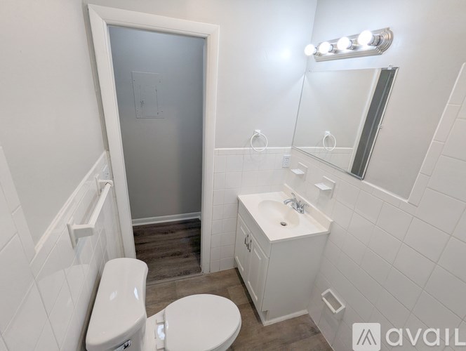 A white bathroom with a toilet, sink, and mirror.