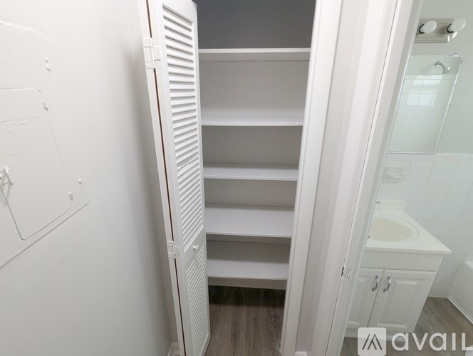 A white pantry with a white fridge and a white bathroom.