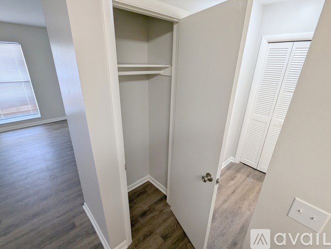 A small white closet with a single shelf is in the corner of a room.