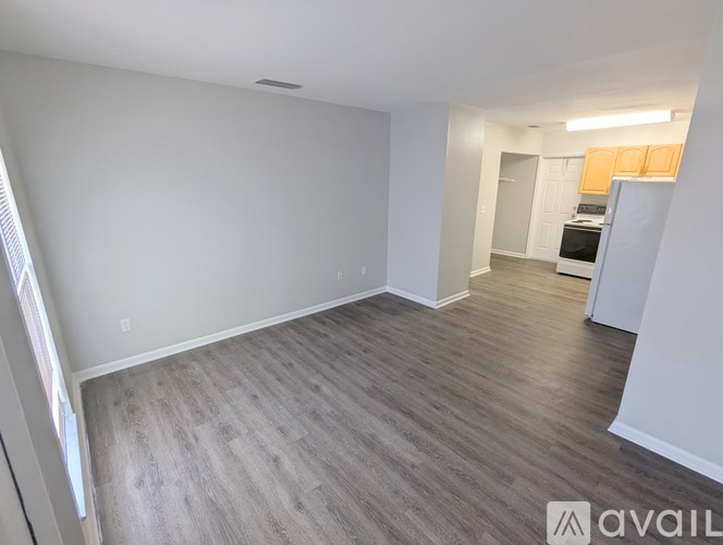 A spacious room with wooden flooring and white walls.