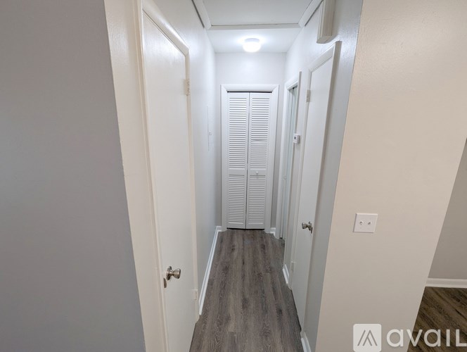 A hallway with white doors and a wooden floor.