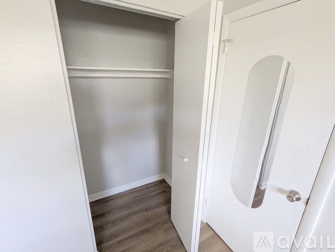 A white closet with a mirror door is open.