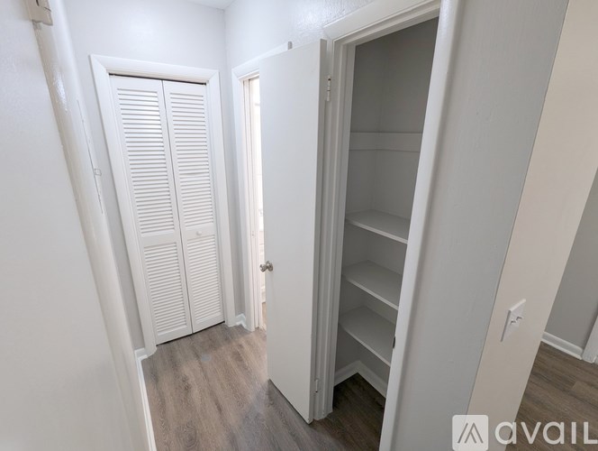 A white closet with shelves and a door is open.