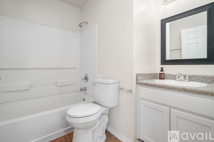 A white toilet in a bathroom with a sink and mirror.
