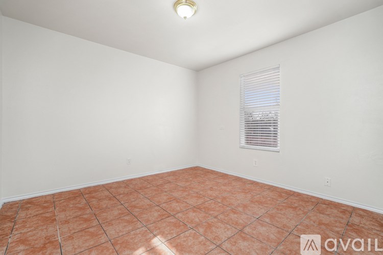 A room with a tiled floor and a window with blinds.