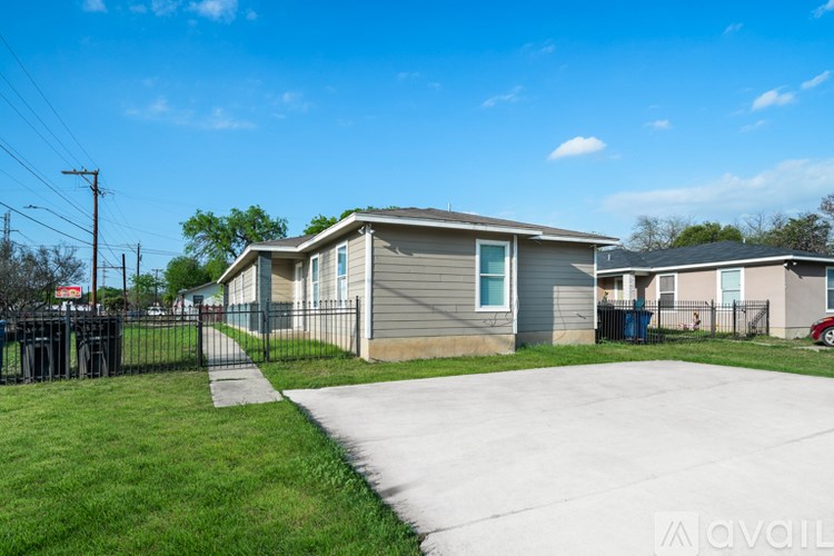 A house with a grey roof and a white fence is available for rent.