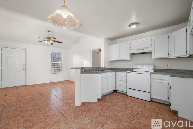 A kitchen with white cabinets and a fan on the ceiling.