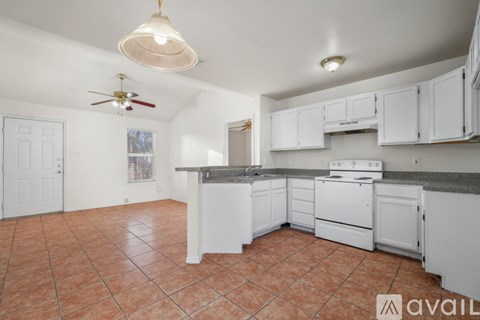 A kitchen with white cabinets and a fan on the ceiling.