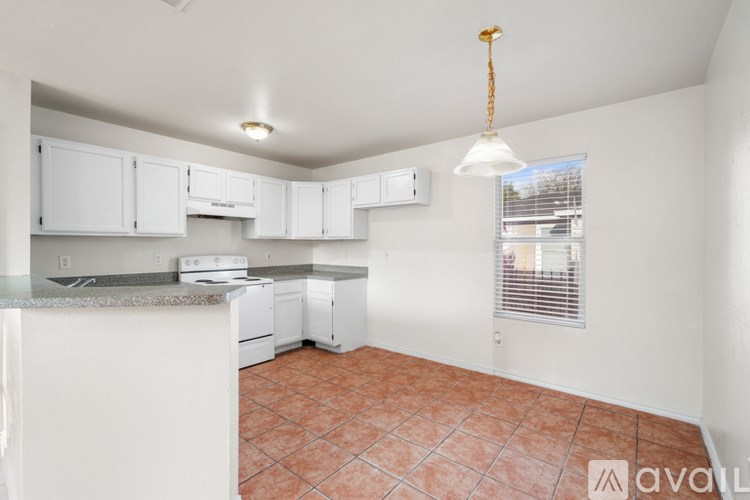 A kitchen with white cabinets and a tiled floor.