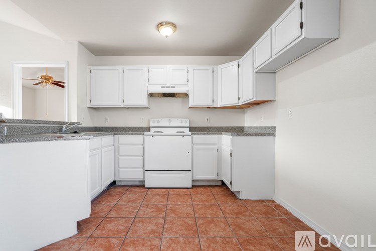 A kitchen with white cabinets and a tiled floor.
