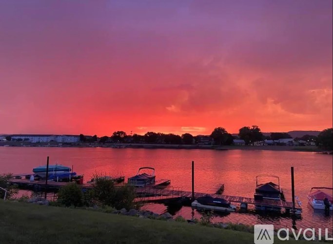 A serene lakeside scene with boats docked at a pier during sunset.
