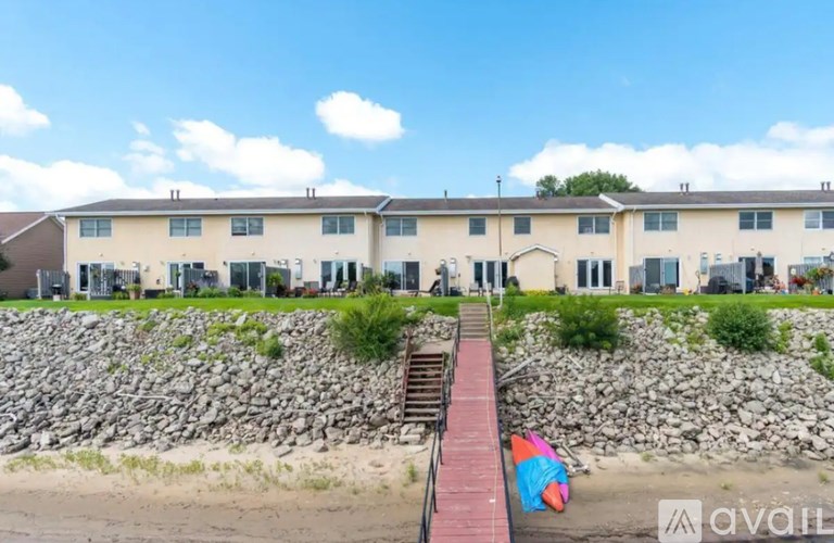A beachfront apartment complex with a stone wall and a red walkway leading to the beach.