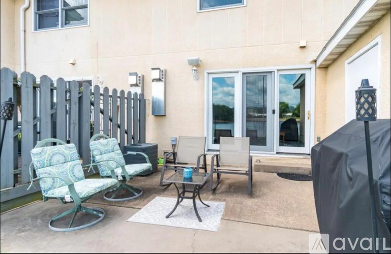 A patio with chairs and a table is set up outside a house.
