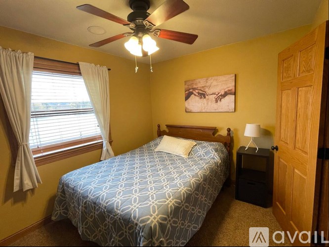 A bedroom with a patterned bedspread and a ceiling fan.