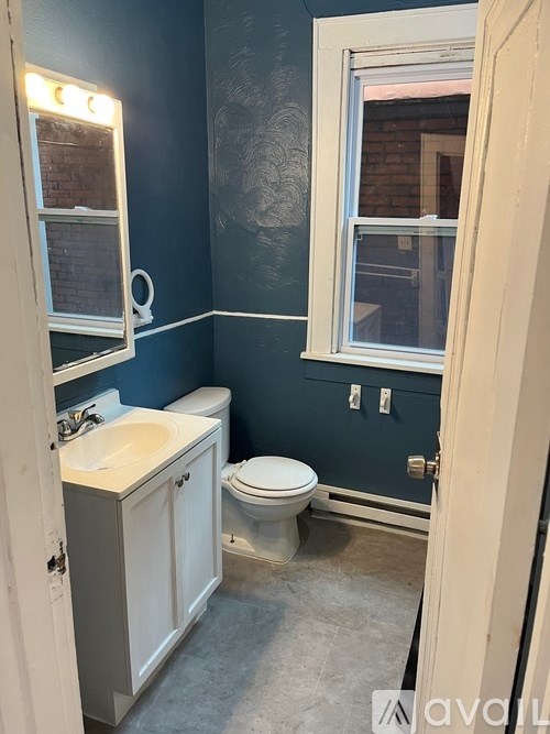 A bathroom with a toilet, sink, and mirror.