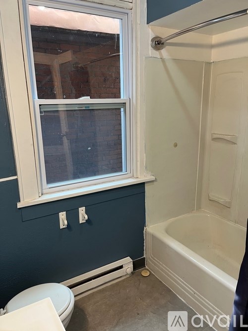 A bathroom with a toilet, tub, and window.