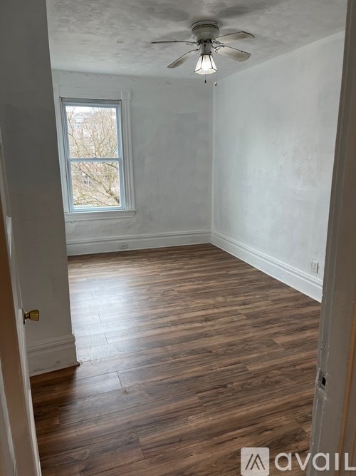 A room with wooden flooring and a ceiling fan.