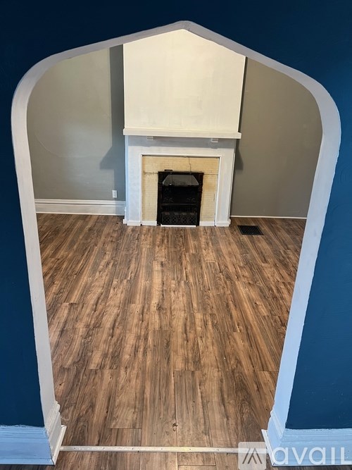 A fireplace with a white mantle and a wooden floor.