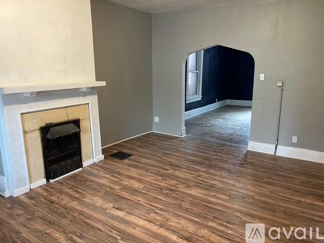 A room with a fireplace and wood flooring.