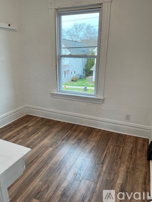 A room with a window and wooden flooring.
