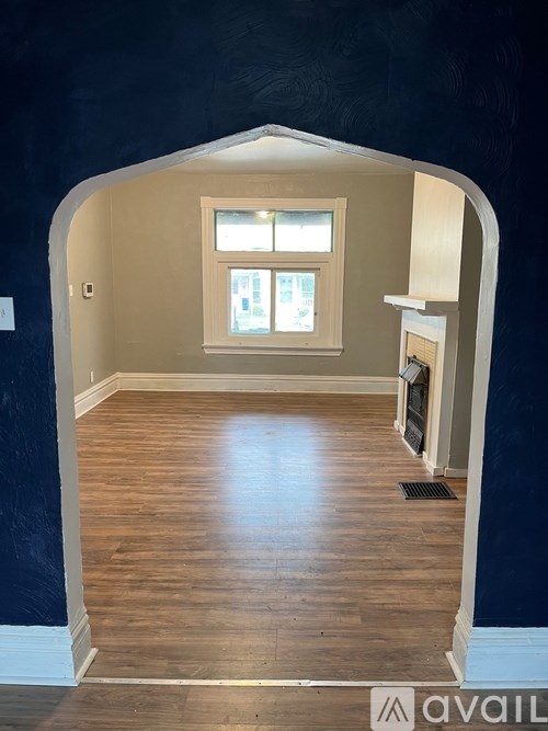 A room with a window and a wooden floor.