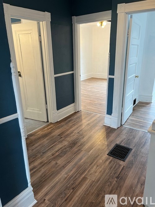 A hallway with white doors and a wooden floor.