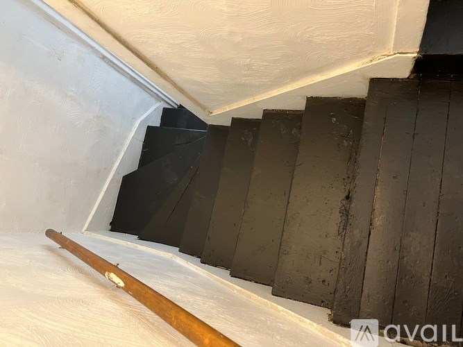 A wooden pole is sticking out of a white wall.