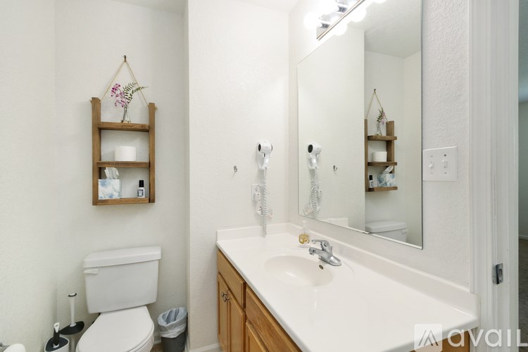 A white bathroom with a toilet, sink, and mirror.