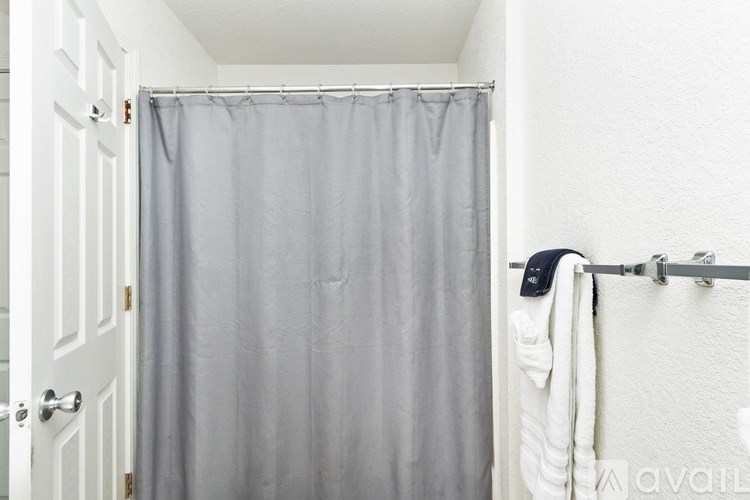 A white door with a grey shower curtain and a white towel hanging on a towel rack.