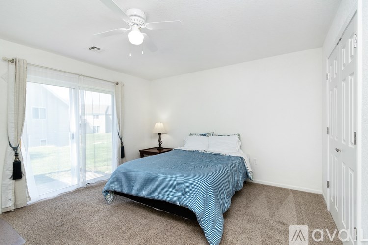 A bedroom with a bed, nightstand, and sliding glass doors.