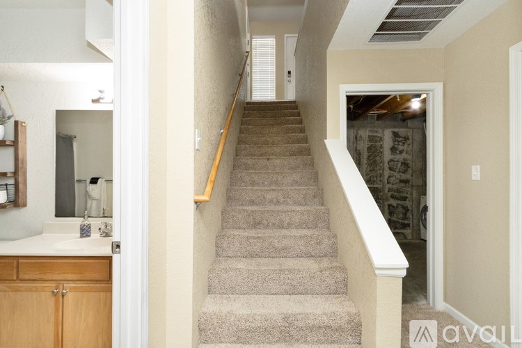 A staircase with a beige carpet and wooden handrail.