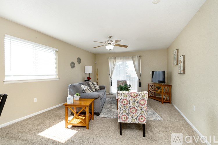 A living room with a grey couch, a wooden coffee table, and a patterned chair.