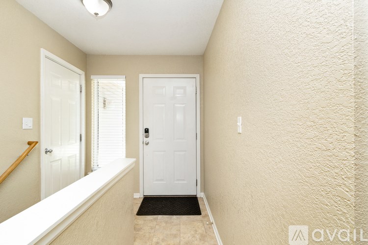 A hallway with a white door and a black doormat.