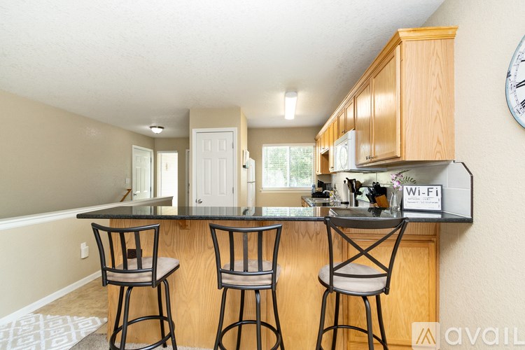 A kitchen with wooden cabinets and a bar area with two stools.