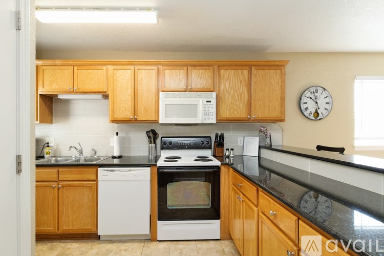 A kitchen with wooden cabinets and black countertops.