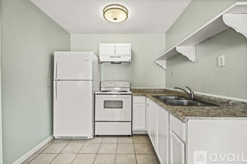A kitchen with a white refrigerator, oven, and sink.