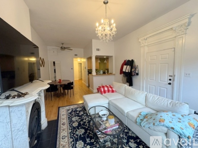 A spacious room with wooden floors and a white fireplace.