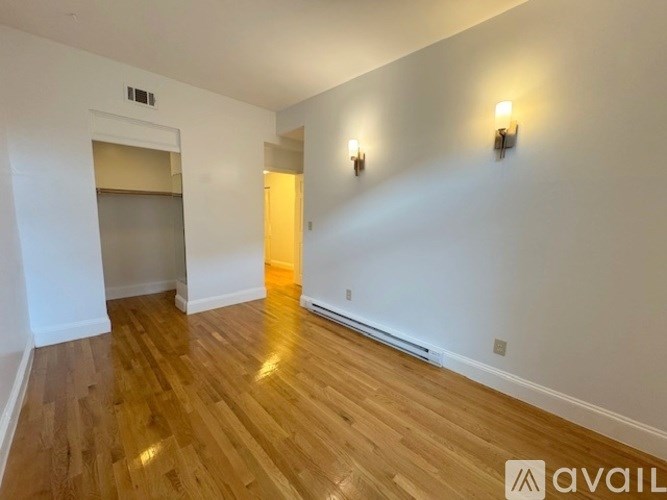 A room with wooden flooring and two wall sconces.