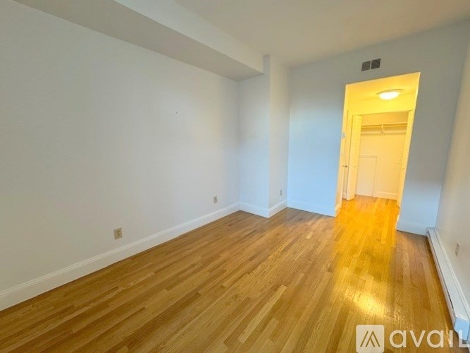 A room with wooden flooring and a doorway leading to another room.