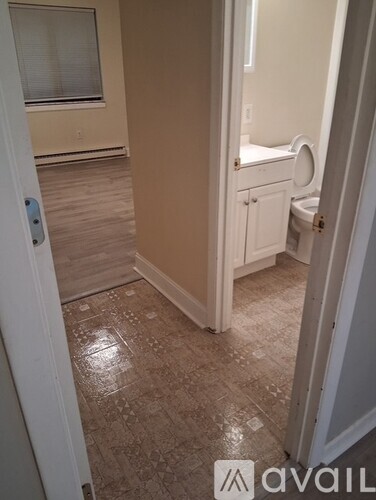 A bathroom with a toilet, sink, and tiled floor.