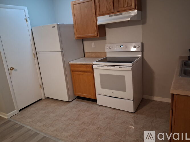 A kitchen with a white refrigerator, a white oven, and wooden cabinets.