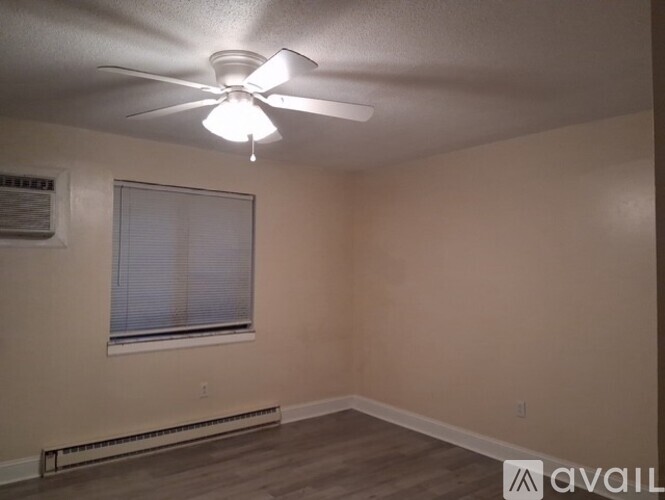 A room with a ceiling fan and a window with blinds.