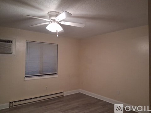 A room with a ceiling fan and a window with blinds.