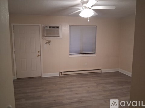 A room with a ceiling fan, a window with blinds, and a door.